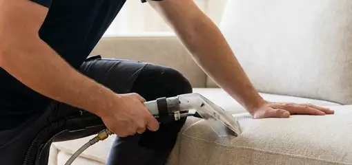 Professional upholstery cleaner deep-cleaning a fabric sofa with a handheld extraction tool, Ann Arbor, MI.